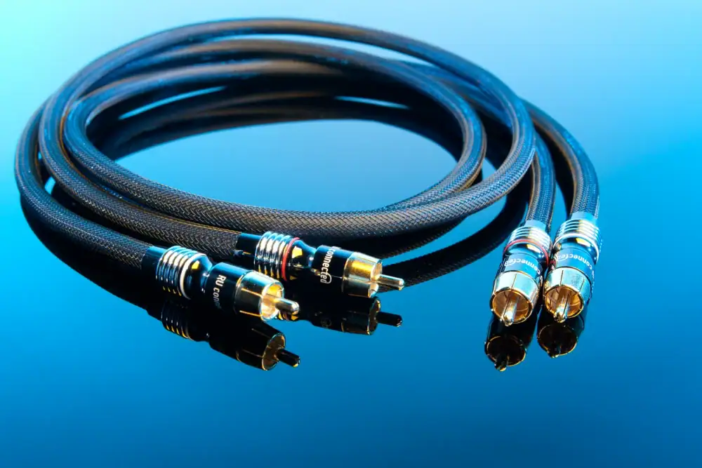 Stereopaar RU connected RCA-kabels met vergulde stekkers en rode en witte ring tegen een blauwe achtergrond.