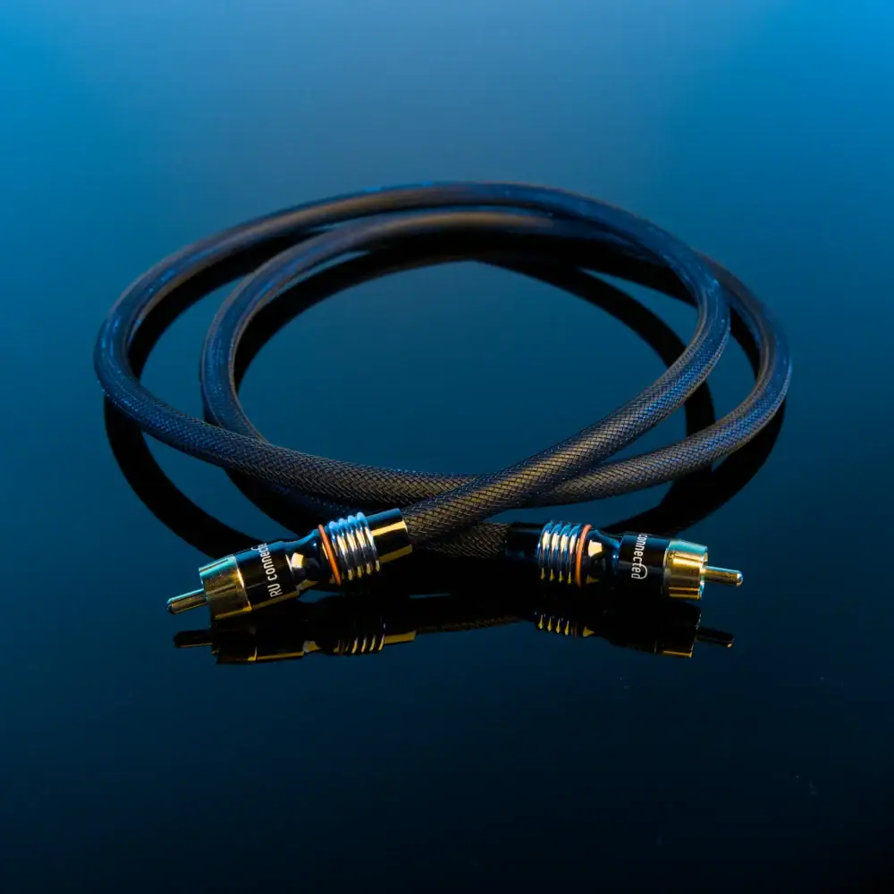 subwoofer-kabel-blauwe-achtergrond Opgerolde subwoofer kabel met twee vergulde RCA-connectoren tegen een blauwe achtergrond.